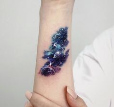 a woman's arm with a tattoo on it that has stars and planets in the sky