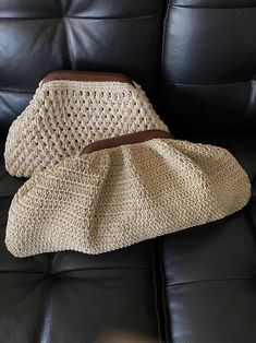 two crocheted purses sitting on top of a black leather couch