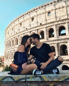 a man and woman sitting next to each other in front of the colossion