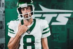 a man in a green and white football uniform is holding his hand on his chest