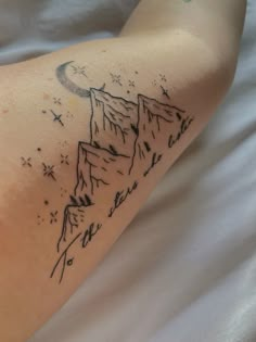 a tattoo on the arm of a person with mountains and stars in the sky above them