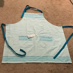 a blue and white striped apron on the floor with a tag hanging from it's side