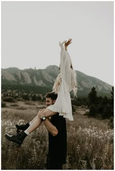 a man carrying a woman on his back in a field with mountains in the background