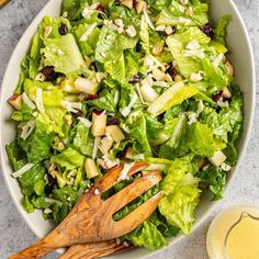 a salad with lettuce, nuts and cranberries in a white bowl