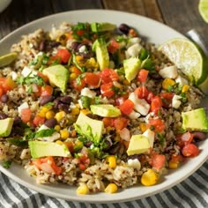 a white plate topped with rice and veggies next to lime wedges on a table