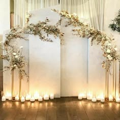 a wedding arch with candles and flowers on the side is decorated with gold leafy vines