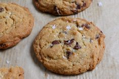 cookies with coconut flakes on top sitting on a piece of parchment paper next to other cookies