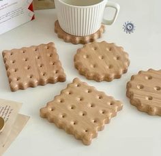 four wooden coasters sitting on top of a table next to a cup and envelope