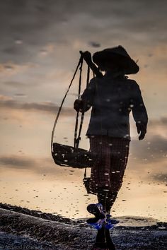 a person walking on the beach with a bag in their hand and an umbrella over his head