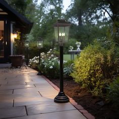 a lamp post sitting in the middle of a walkway next to some bushes and trees