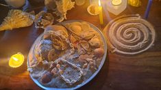 an assortment of seashells on a plate with candles and other items around it