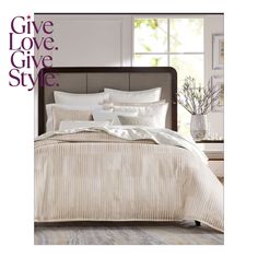 a bed with white sheets and pillows in front of a window that says give love, give style