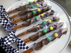 there are many candy sticks on the plate with checkered ribbon around them and some candies wrapped in cellophane