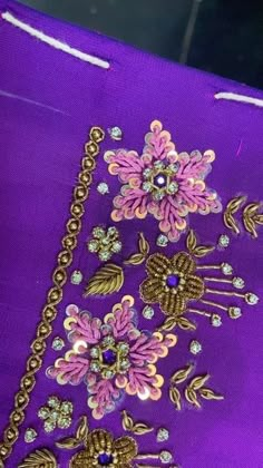 a purple bag with flowers and jewels on it's side, sitting on a table