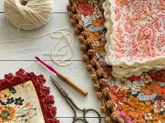 some crochet is laying on a table next to yarn and scissors