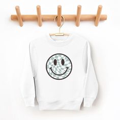 Looking for a cute sweatshirt for your kids? We have the perfect Checker Board Smiley Face graphic sweatshirt addition to their closet! Also available in toddler sweatshirts. Cute Crew Neck Sweatshirt For School, Playful White Long Sleeve Sweatshirt, Cute Sweatshirt With Funny Print And Crew Neck, Cute Crew Neck Sweatshirt With Funny Print, Playful Crew Neck Sweater With Graphic Print, Playful Cotton Crew Neck Sweatshirt, Cute White School Sweatshirt, Cute White Sweatshirt For School, White Sporty Sweatshirt With Cartoon Print