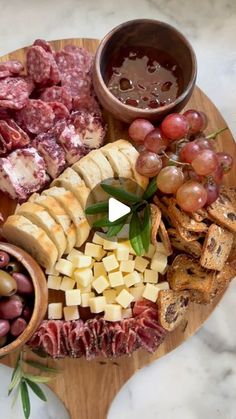 an assortment of meats and cheeses on a wooden platter with bowls of fruit