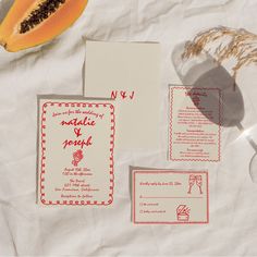 the wedding stationery is laid out on top of the table with fruit and paper