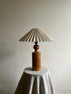 a table with a lamp on top of it next to a white wall and floor