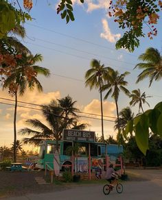 a man riding a bike past a food truck with palm trees in the foreground