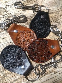 three leather keychains with intricate designs on them