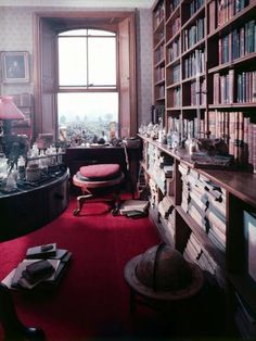 a room with many bookshelves and a red carpet on the floor in front of a large window