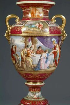 an ornately painted vase with gold trimmings and red accents on the sides