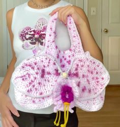 a woman holding a pink crocheted purse in her right hand and wearing a white t - shirt