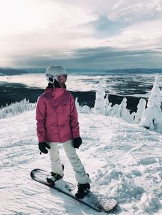 a snowboarder stands on the top of a snowy mountain