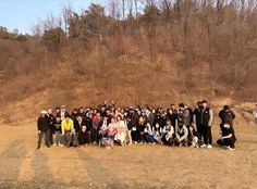 a group of people standing next to each other on top of a grass covered field