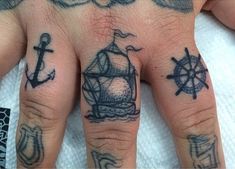 a person's hand with tattoos on it and an anchor, ship wheel and compass