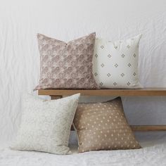 four pillows on a wooden shelf against a white wall