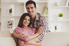 a young man and woman hugging on the couch in their living room stock photo - 789