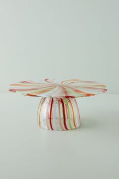 a multicolored glass cake stand on a white table with red, green, yellow and orange stripes