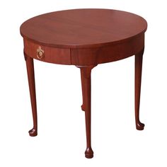 an oval wooden table with one drawer on the top and two legs at the bottom