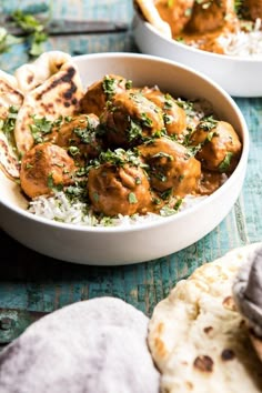 a bowl filled with meat and vegetables on top of rice next to pita bread