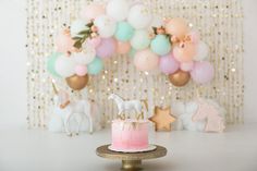 there is a cake on the table with balloons in the background and decorations around it