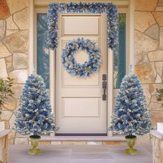 a front door decorated with blue christmas wreaths and trees next to it is an entry way