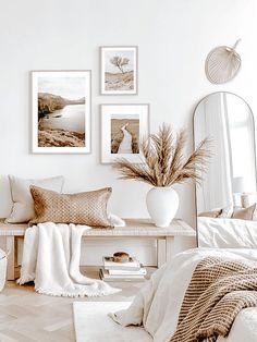 a white room with pictures on the wall and a bench in front of some pillows