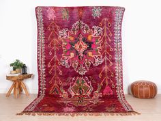 an antique persian rug is displayed on the floor in front of a white wall and wooden table