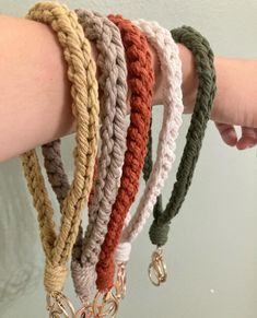 a woman's arm with five bracelets on it, one is made from yarn and the other has charms