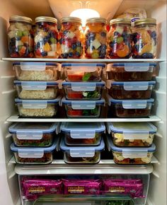 an open refrigerator filled with lots of food and containers full of fruit, vegetables, and other foods