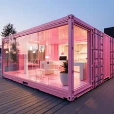 a pink shipping container sitting on top of a wooden deck next to a table and chairs