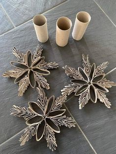 four metal snowflakes sitting on top of a tile floor next to two cups