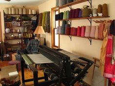 a room filled with lots of different types of yarn on shelves next to a table