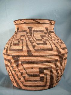 a woven basket with an intricate design on it's side, sitting on a blue background