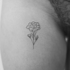 a small flower tattoo on the back of a woman's left shoulder and breast