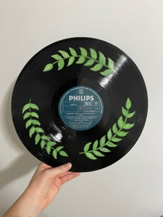 a person holding up a black record with green leaves on it