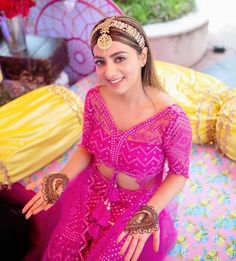 a woman in a pink dress sitting on a bed with her hands out to the side