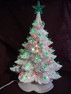 a white ceramic christmas tree with lights and a green star on it's top